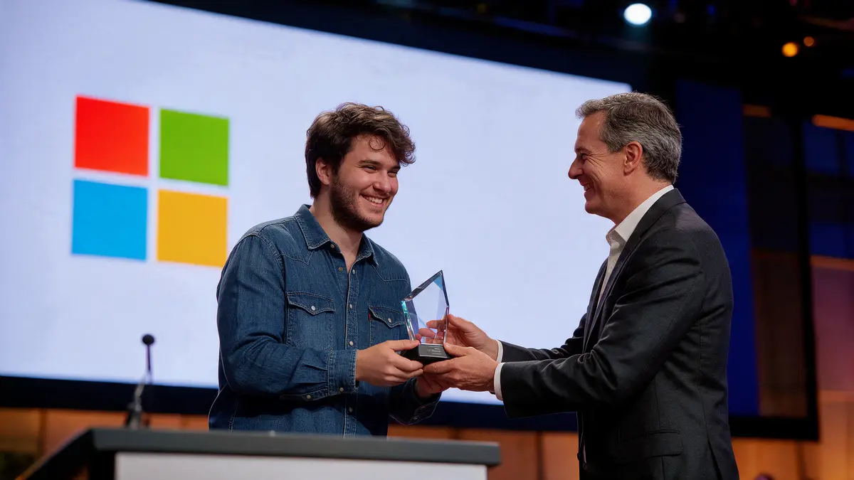 Jesús Núñez recibe el trofeo del campeonato sobre el escenario, con el logotipo de Microsoft proyectado en la pantalla del fondo
